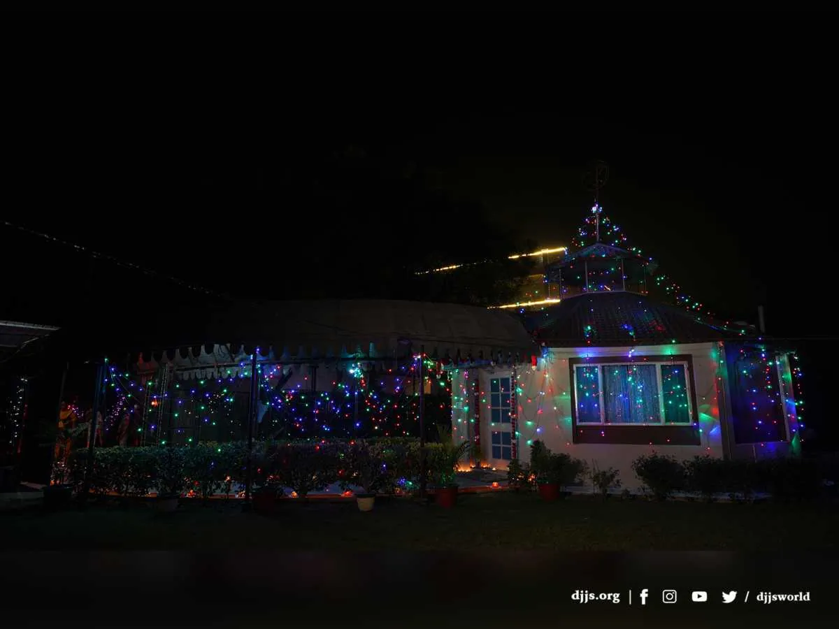 A building at Divya Dham Ashram strung with festive lights for Diwali 2021, earthen lamps along its garden