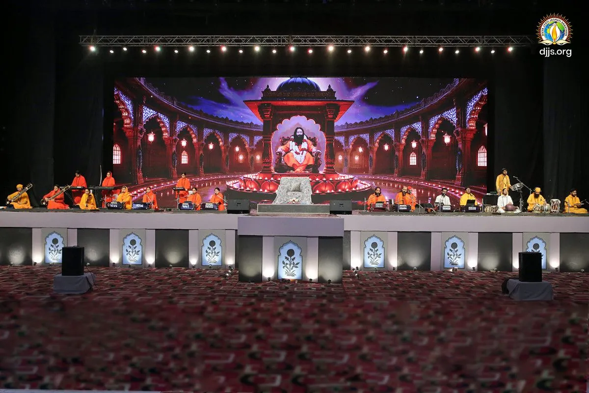 A night stage beneath an arched screen at the monthly spiritual congregation at Divya Dham Ashram, February 2026